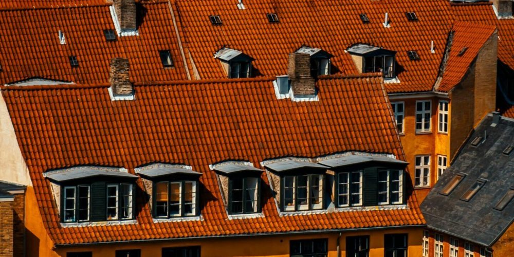 Aerial view of Copenhagen's urban rooftops with vibrant red tiles and classic architecture.